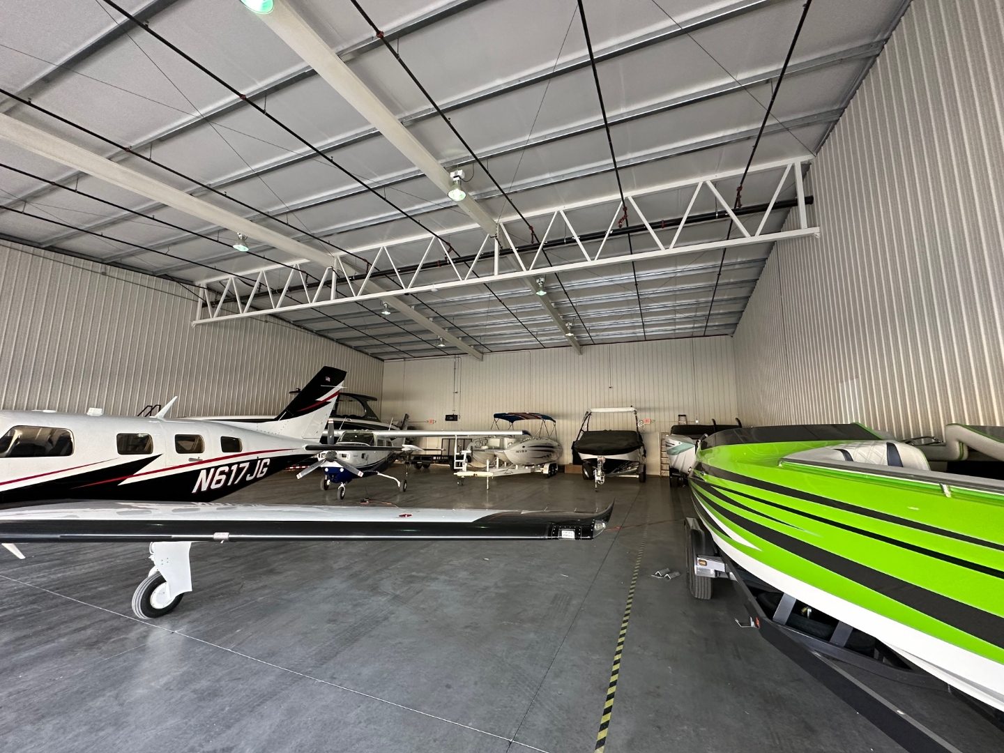 Hangar interior with a plane and colorful boats sharing daylight floor space